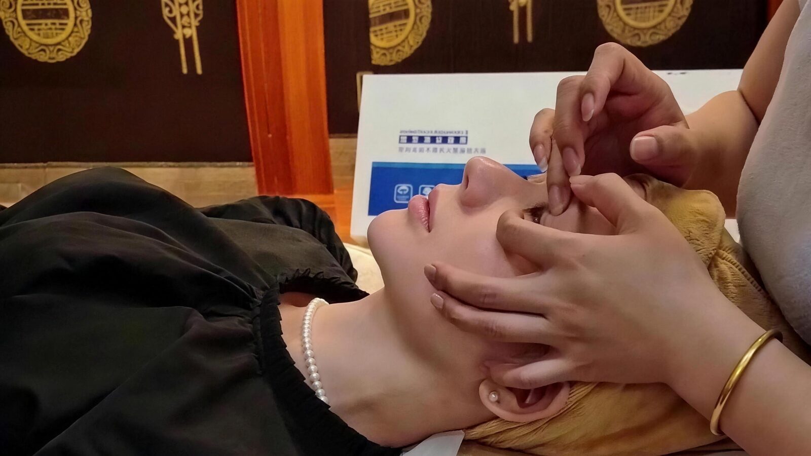 A Pamperloft therapist doing a gentle eye massage along a guest's brow and upper eye area, part of a non-surgical eye bag treatment in Bedok, Singapore